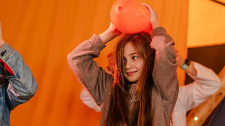 Young girl rubbing balloon on her head to create static