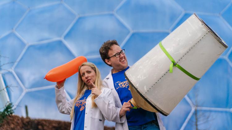 Scientist woman holding balloon and man holding large drum