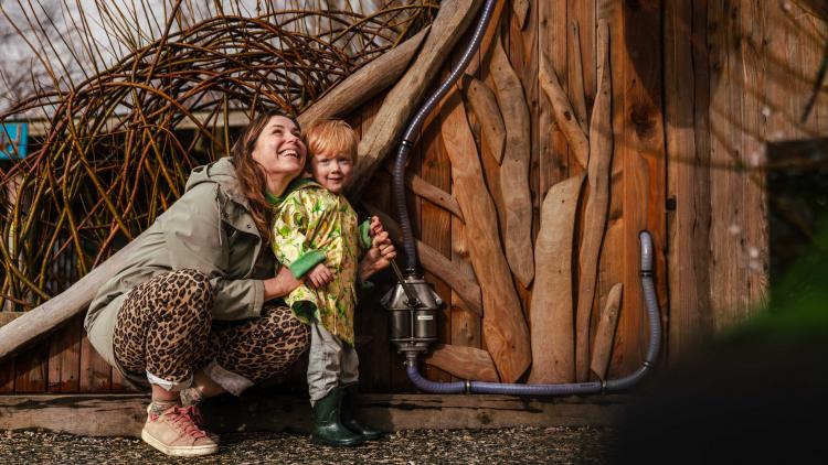 Mother crouching down with young child smiling in outdoor playground