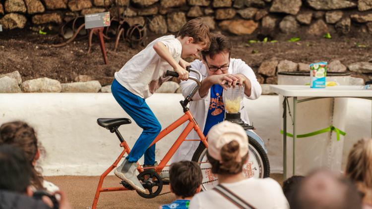 Boy on a modified bike cycling hard to make a blender work