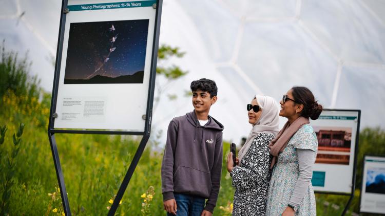 Family looking at photography exhibition in the Outdoor Gardens of the Eden Project