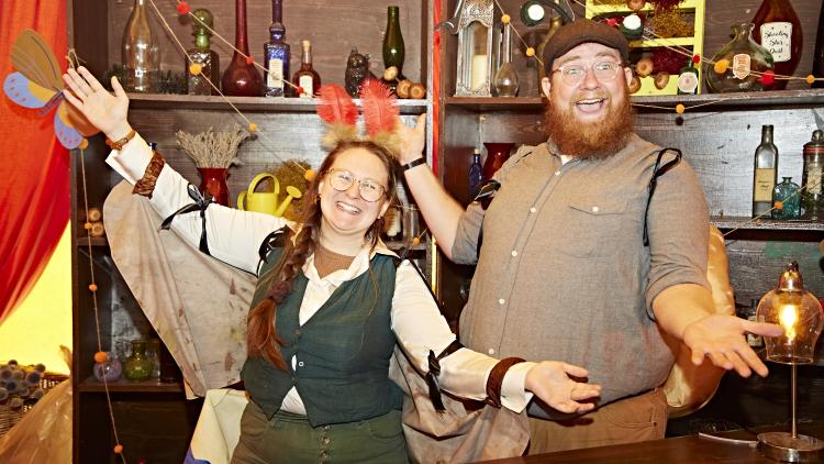 Actors dressed up as bugs posing with their arms open wide smiling
