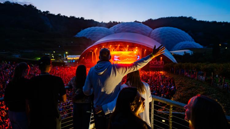 People on platform watching concert with hands raised