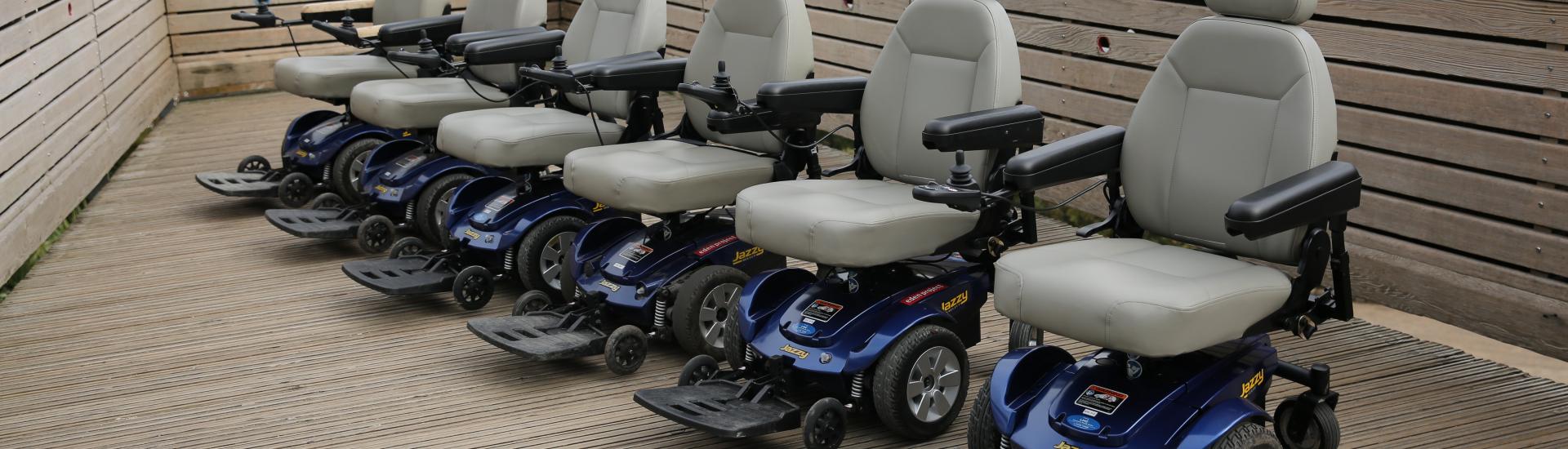 A line of powered wheelchairs with the eden biomes in the background