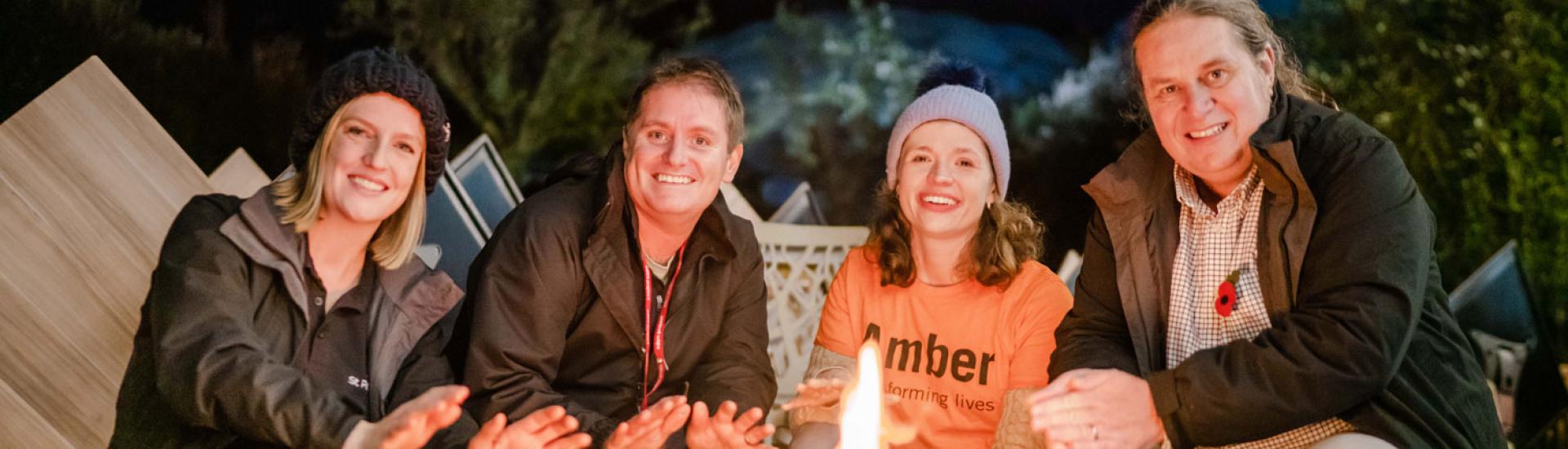 Group sitting by a fire pit in the evening at Eden