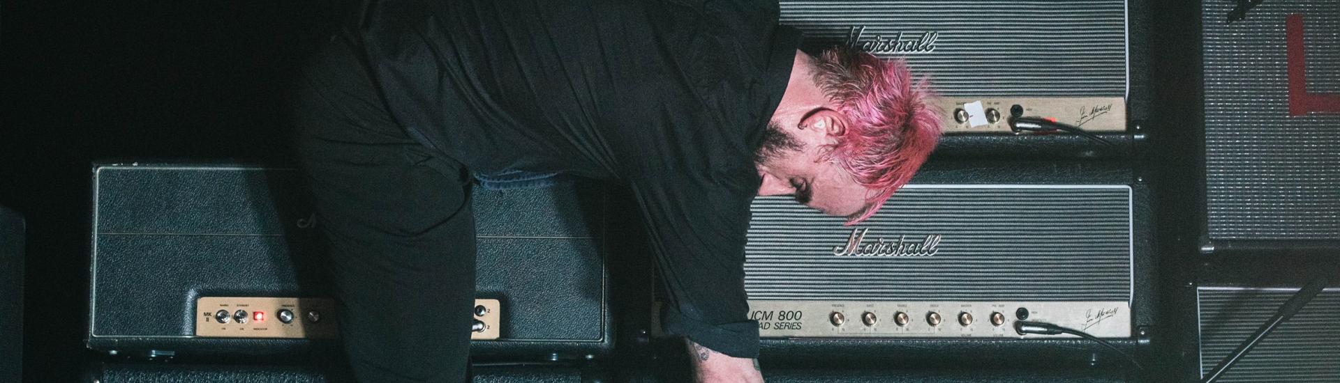 IDLES band member holding microphone to an amp