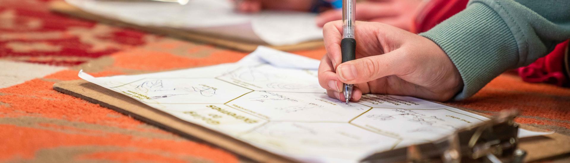 A close up of two children writing on clipboards 