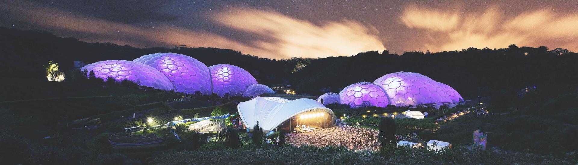 Wide view of a Sessions concert under a starry sky at Eden with the Biomes lit up purple