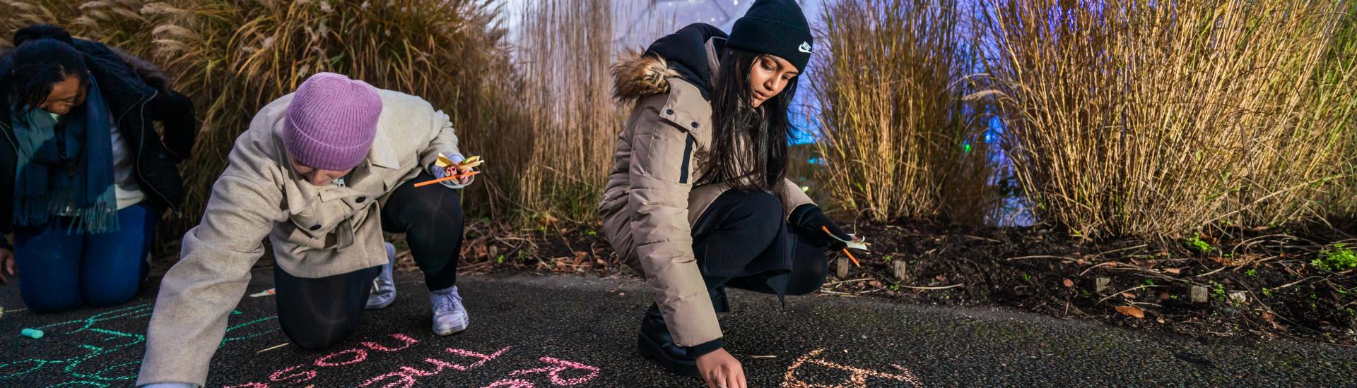 Teachers writing in chalk on the paths in front of Eden's Biomes