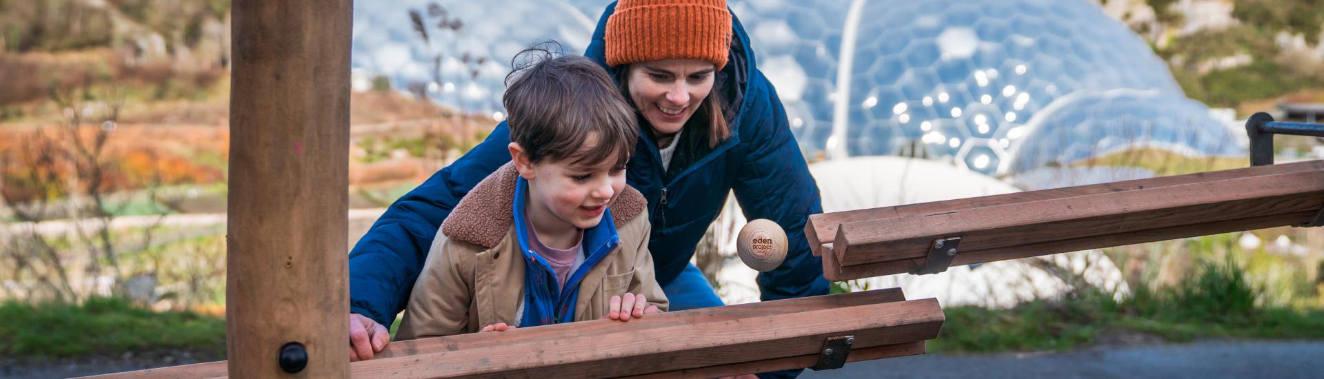 Mother and son watching giant marble drop down a run at the Eden Project