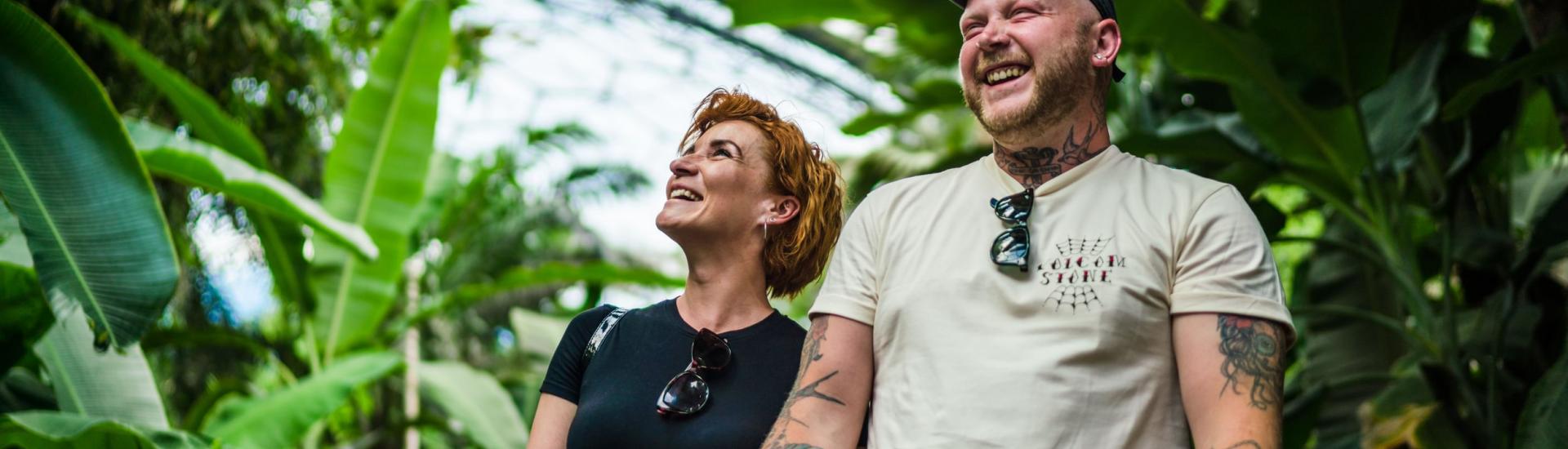 A couple stand side by side looking up and smiling in the Rainforest Biome